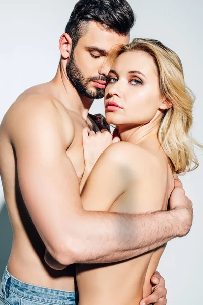 Shirtless man hugging naked blonde woman looking at camera on white — Stock Photo