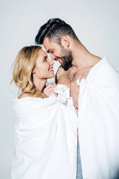 Casal feliz olhando um para o outro enquanto segurando cobertor no branco — Fotografia de Stock