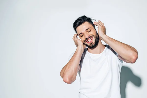 Веселий чоловік слухає музику в навушниках і посміхається на білому — стокове фото