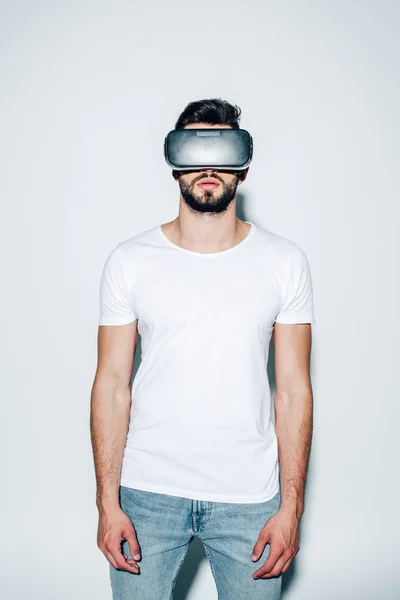 Hombre barbudo con auriculares de realidad virtual mientras está de pie en blanco - foto de stock