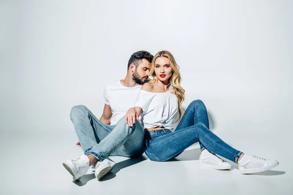 Handsome bearded man sitting and looking at attractive blonde girl on white — Stock Photo