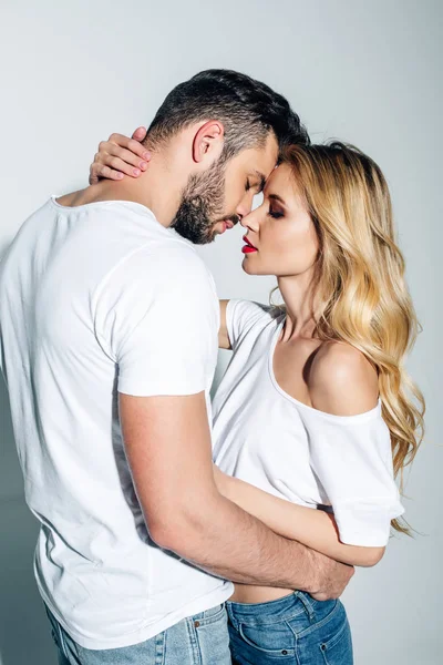 Schöner Mann mit geschlossenen Augen umarmt blondes Mädchen auf weißem — Stockfoto