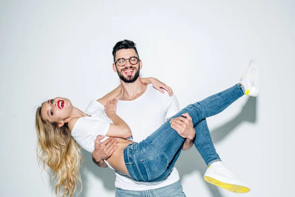 Happy man in glasses holding in arms attractive blonde girl on white — Stock Photo