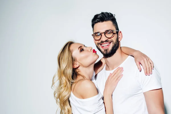 Mujer alegre con cara de pato mirando hombre feliz en gafas en blanco - foto de stock