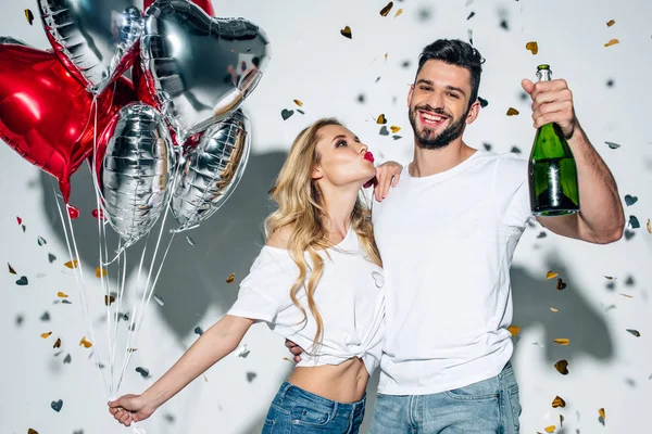 Selektiver Fokus eines gut gelaunten bärtigen Mannes mit Champagnerflasche in der Nähe einer Frau mit Entengesicht auf weißem Hintergrund — Stockfoto