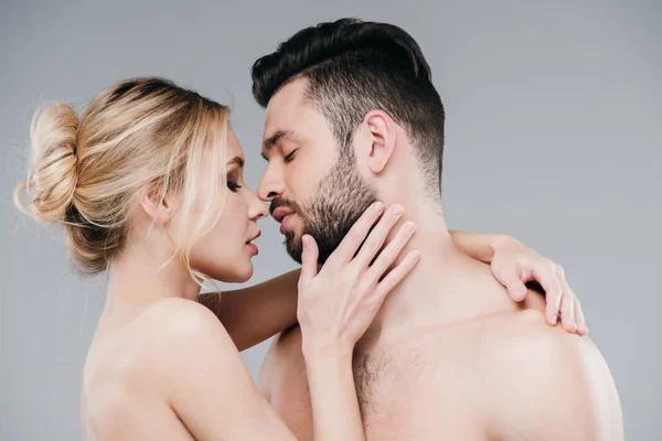 Beautiful nude young woman hugging bearded shirtless man on grey — Stock Photo