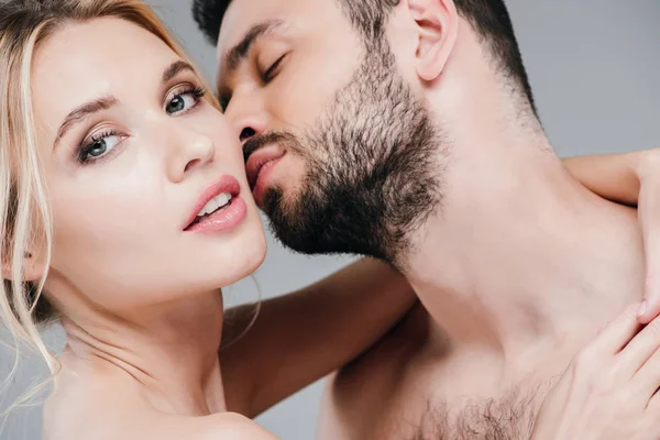 Nahaufnahme eines hübschen Mannes, der die Wange eines attraktiven blonden Mädchens auf grau küsst — Stockfoto