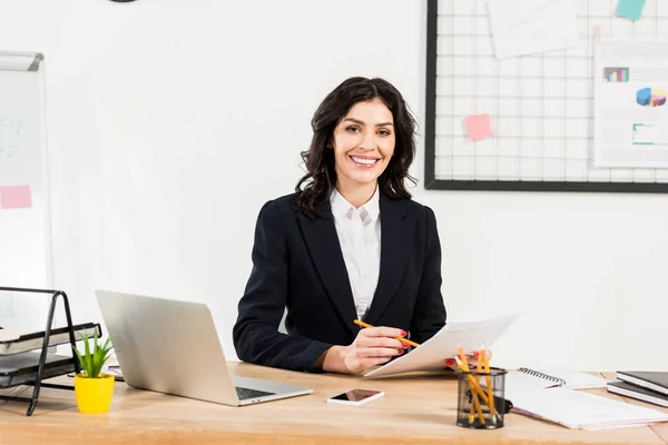 Cheerful recruiter in formal wear holding document and pencil in office — Stock Photo