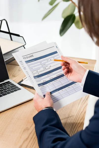 Selective focus of man holding resume and pencil near laptop — Stock Photo