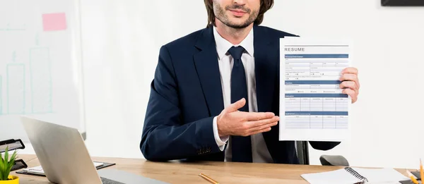 Panoramic shot of recruiter gesturing while holding resume in office — Stock Photo