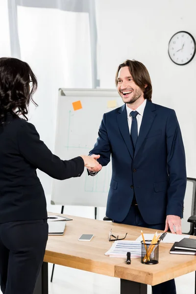 Handsome recruiter shaking hands with brunette woman in office — Stock Photo