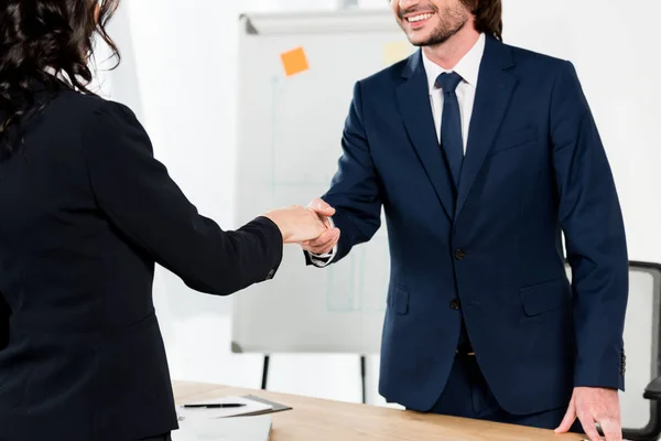 Abgeschnittene Ansicht eines glücklichen Personalvermittlers, der brünetten Frau im Büro die Hand schüttelt — Stockfoto