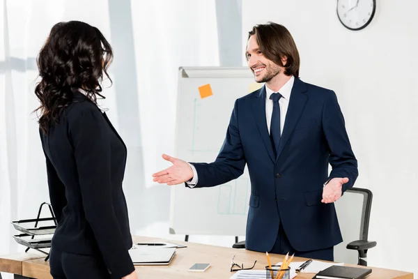 Bonito recrutador gestos perto morena mulher no escritório — Stock Photo