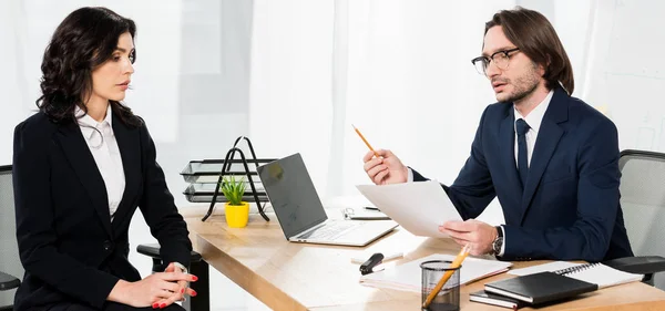 Panoramic shot of handsome recruiter holding paper near attractive woman with clenched hands — Stock Photo