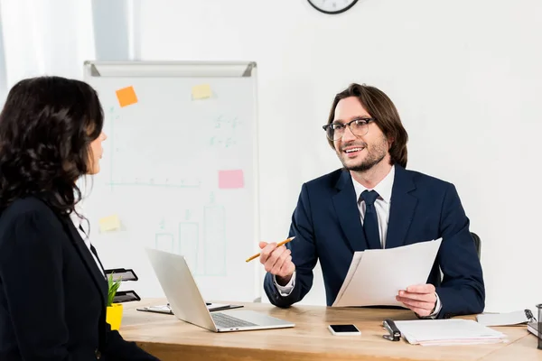 Foco seletivo de recrutador feliz em óculos segurando documentos e olhando para a mulher — Stock Photo