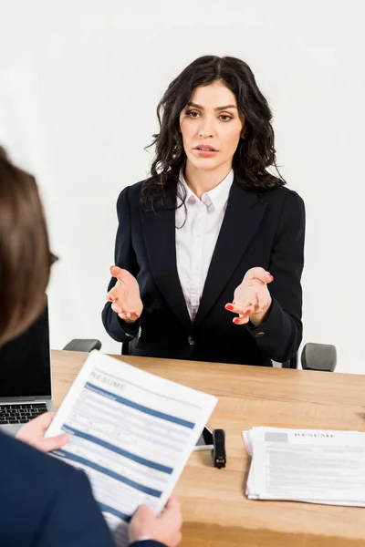 Selective focus of attractive woman gesturing while talking with recruiter in office — Stock Photo