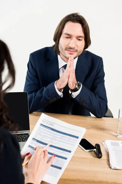 Selective focus of handsome man sitting with praying hands near recruiter — Stock Photo