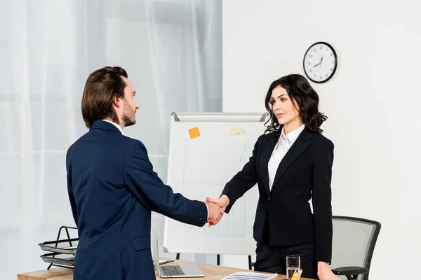 Attractive recruiter shaking hands with handsome employee in office — Stock Photo