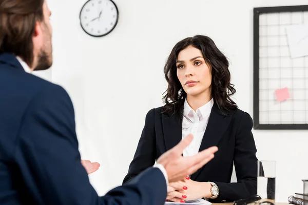 Selective focus of attractive recruiter looking at man gesturing during job interview — Stock Photo