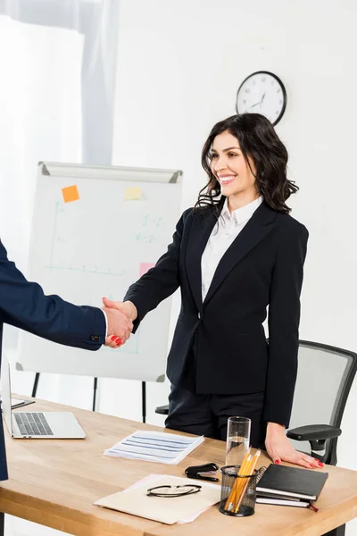 Vista recortada del hombre estrechando la mano con reclutador feliz en la oficina - foto de stock