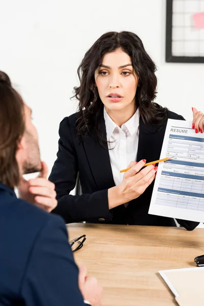 Selective focus of attractive recruiter holding resume near man during job interview — Stock Photo
