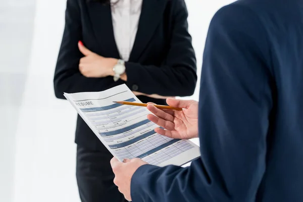 Cropped view of woman standing with crossed arms near man with resume — Stock Photo