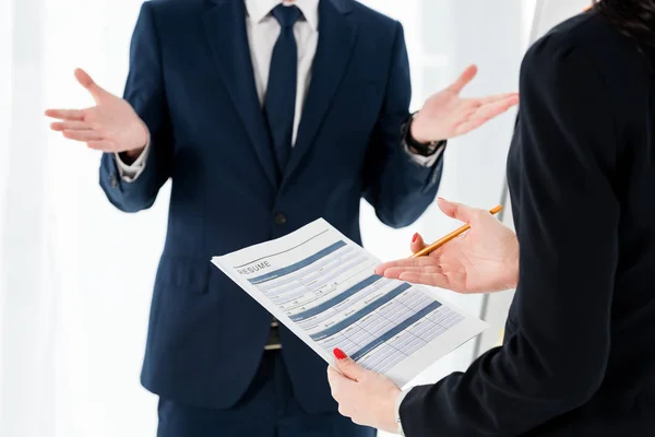 Recortado vista de la mujer sosteniendo curriculum vitae y lápiz cerca gesto hombre - foto de stock