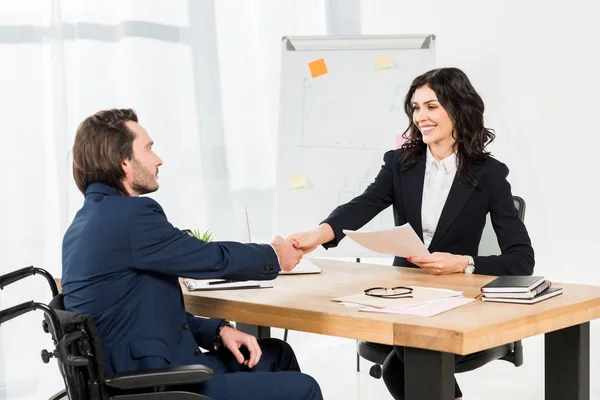 Glücklicher Personalvermittler schüttelt behinderten Mann die Hand, während er Dokumente im Büro hält — Stockfoto