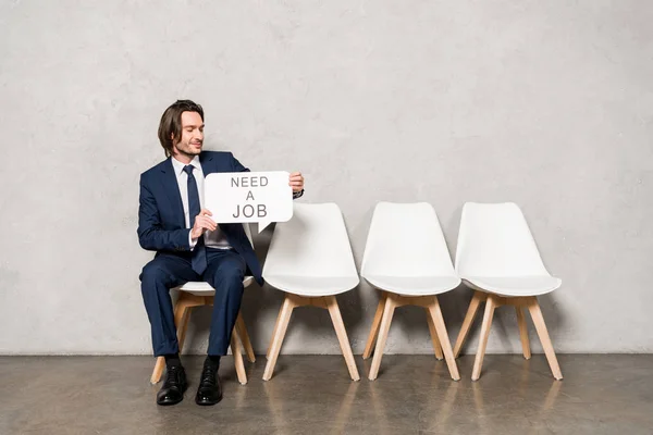 Cheerful employee holding speech bubble with need a job lettering — Stock Photo