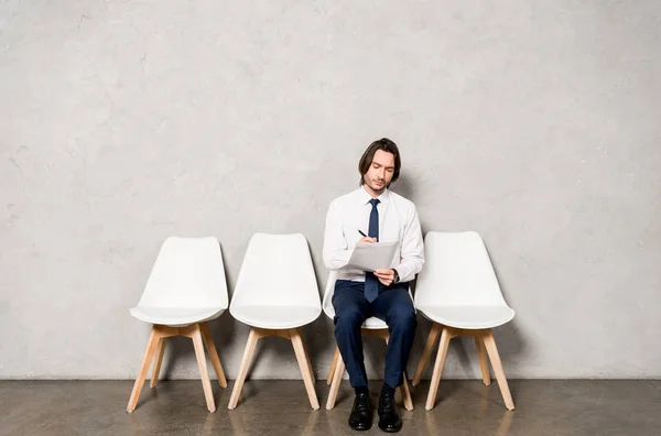 Homem bonito sentado na cadeira enquanto espera entrevista de emprego no escritório — Fotografia de Stock