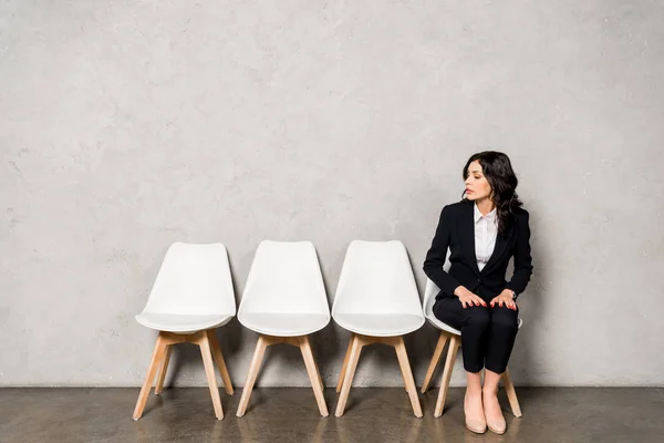 Attractive brunette woman in formal wear sitting on chair before job interview — Stock Photo