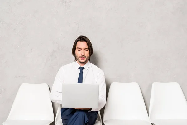 Hombre guapo en ropa formal usando teléfono inteligente mientras está sentado en la silla — Stock Photo