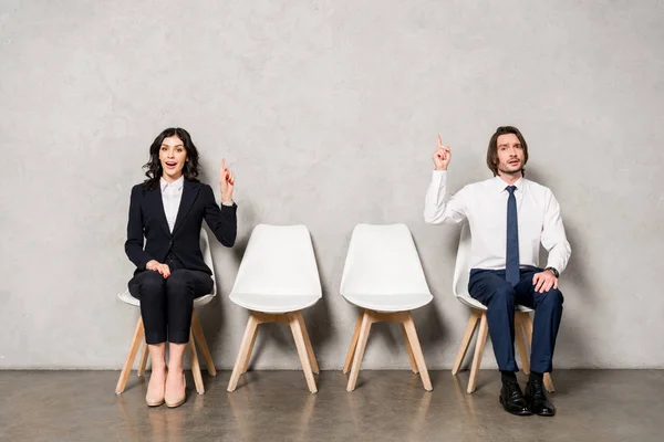 Happy brunette woman and handsome man gesturing while sitting on chairs — Stock Photo