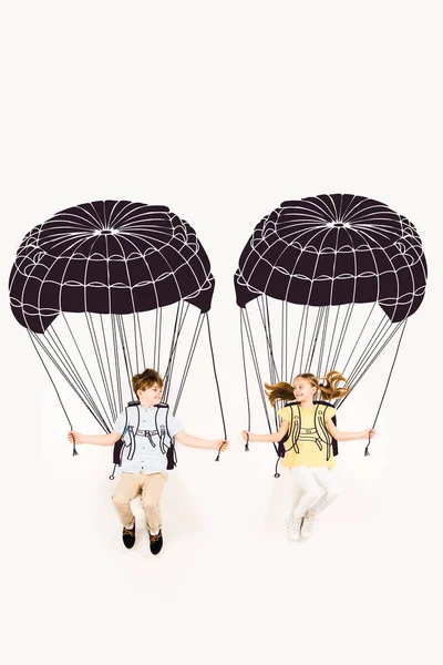 Вид зверху веселий хлопчик і щаслива дівчина тримає парашути під час польоту на білому — стокове фото
