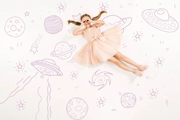 Top view of cheerful kid in pink dress with hands near eyes in space on white — Stock Photo