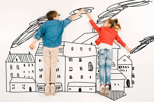 Top view of cute children gesturing while flying near houses on white — Stock Photo