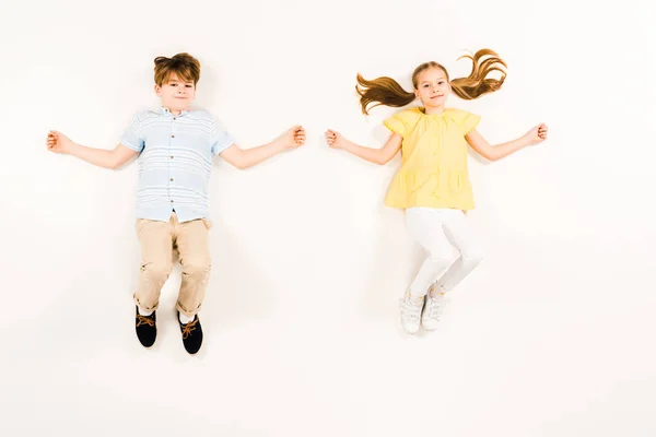 Top view of happy children looking at camera and smiling on white — Stock Photo