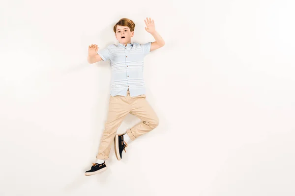 Top view of scared kid gesturing while screaming and lying on white — Stock Photo