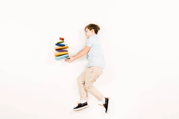 Vista superior de niño lindo sosteniendo libros de colores en blanco - foto de stock