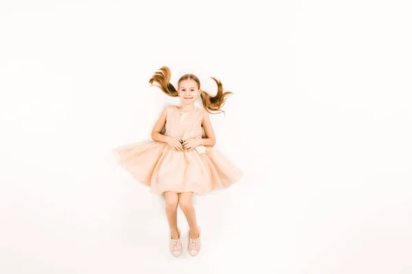 Top view of happy child in pink dress looking at camera on white — Stock Photo