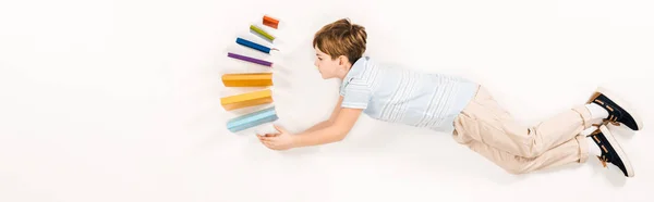 Plan panoramique de mignon enfant tenant des livres colorés tout en volant sur blanc — Photo de stock