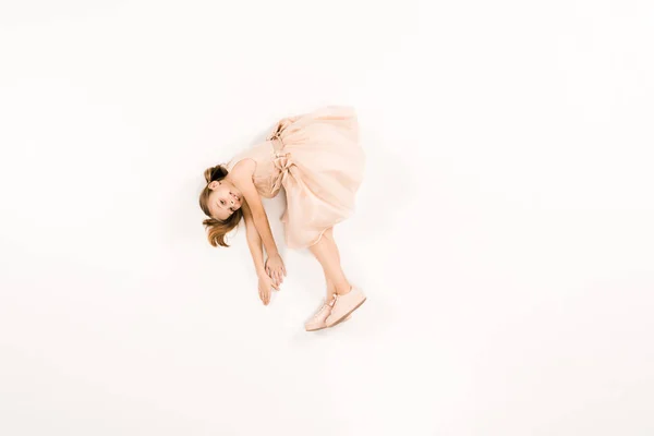 Vue de dessus de l'adorable enfant en robe regardant la caméra sur blanc — Photo de stock