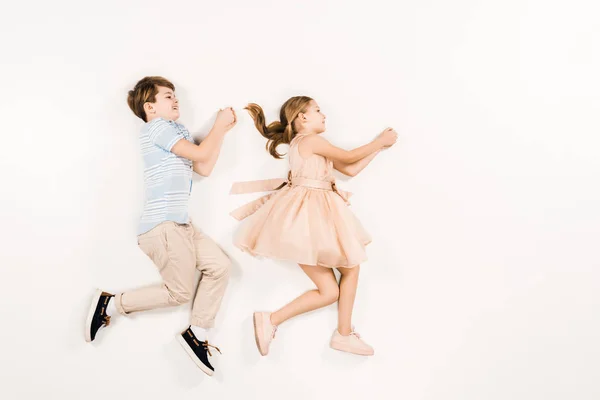 Top view of cheerful kids gesturing while lying on white — Stock Photo