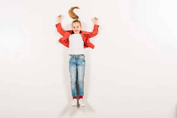 Vue de dessus de l'enfant heureux avec les mains au-dessus de la tête couché sur blanc — Photo de stock