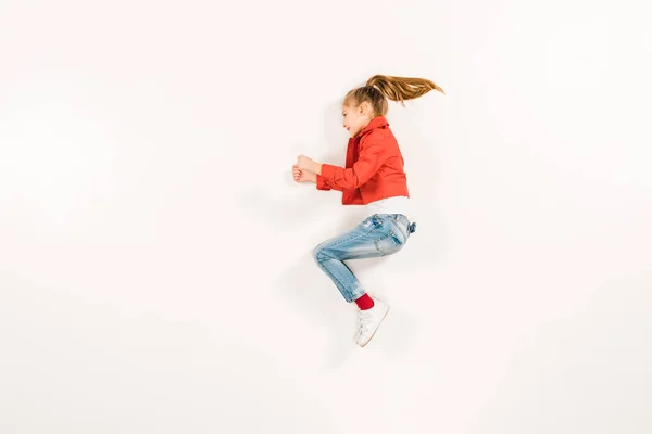 Vue du haut de l'enfant gai en jeans bleus gesticulant sur blanc — Photo de stock