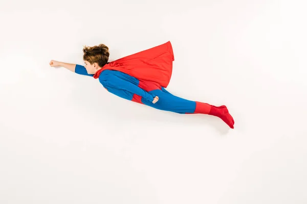 Vista dall'alto di adorabile bambino in costume da super eroe che vola sul bianco — Foto stock