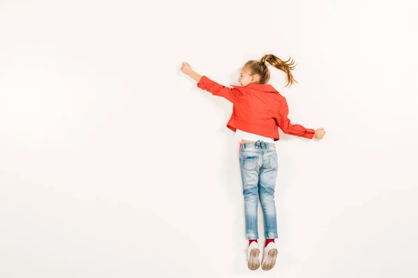 Blick von oben auf ein glückliches Kind in blauen Jeans, das gestikuliert, während es auf weiß liegt — Stockfoto