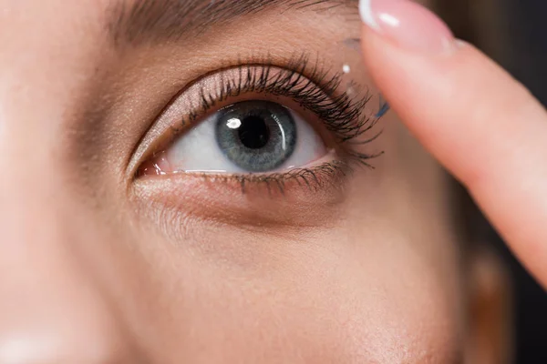 Ausgeschnittene Ansicht des Mädchens, das Kontaktlinse isoliert auf Schwarz anbringt — Stockfoto