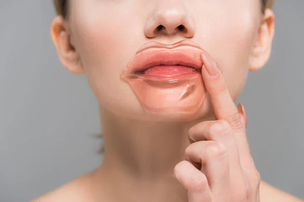 Abgeschnittene Ansicht einer jungen Frau, die Lippenmaske isoliert auf grau aufträgt — Stockfoto