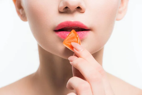 Vista recortada de la mujer sosteniendo caramelo de jalea naranja aislado en blanco - foto de stock